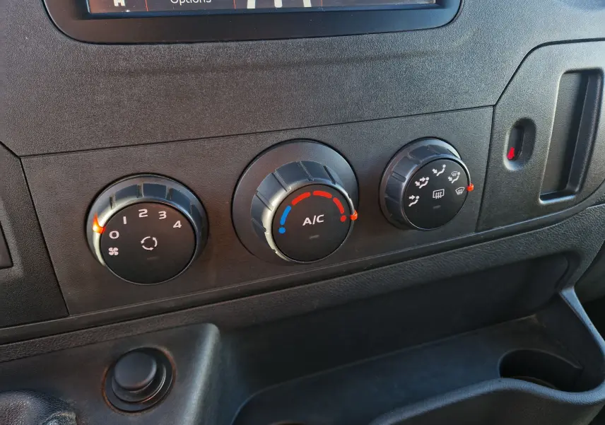 Gros plan sur les commandes de climatisation du tableau de bord du Renault Master blanc, avec réglages manuels et écran partiel en haut.