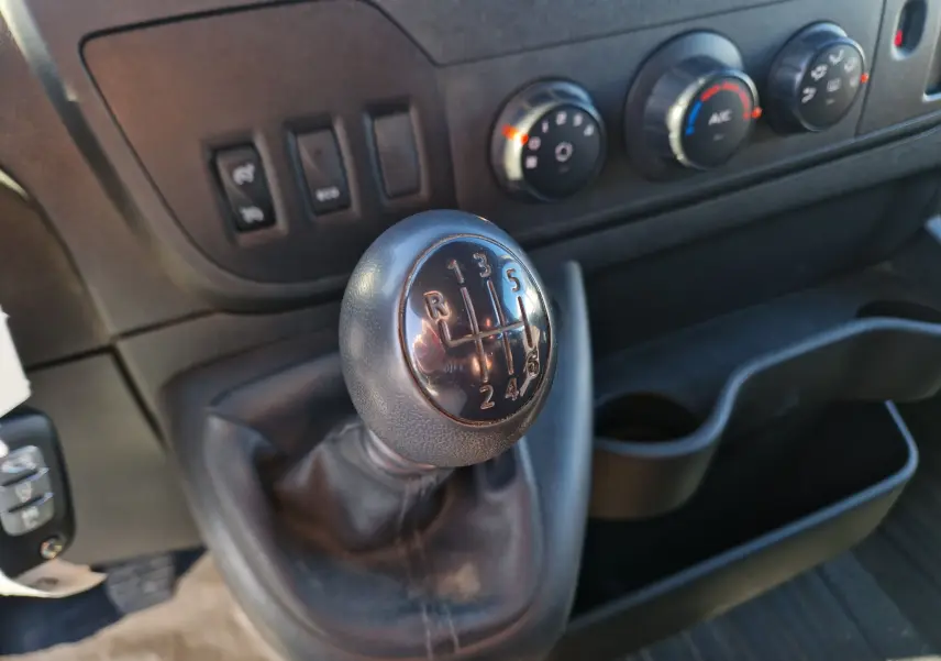 Gros plan sur le levier de vitesses manuel noir du Renault Master cabine approfondie, avec commandes de climatisation en arrière-plan.