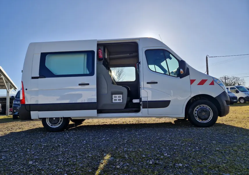 Profil droit d’un Renault Master cabine approfondie blanc avec porte latérale ouverte montrant l’intérieur et un extincteur fixé.