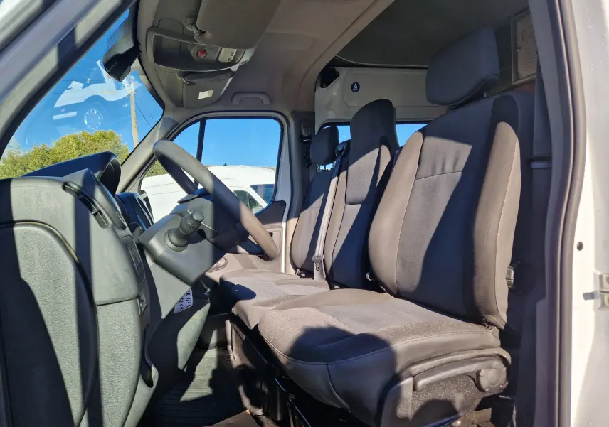 Vue intérieure côté conducteur du Renault Master blanc 2019, montrant les sièges avant et le volant à droite.