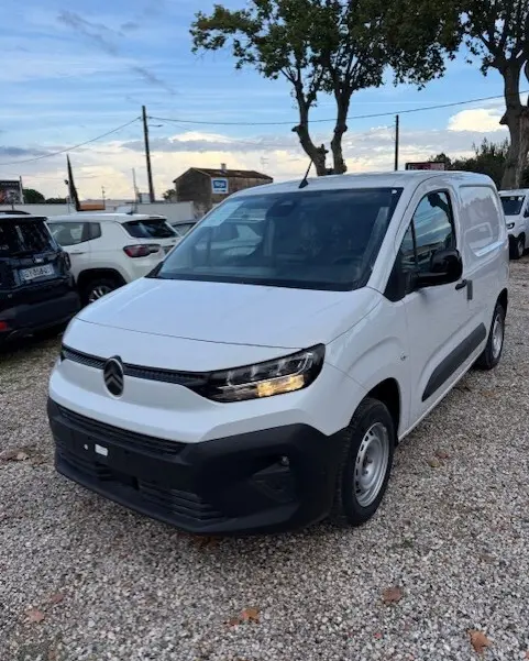 Vue 3/4 avant droite d'un Citroën Berlingo blanc 2026 version Van M Diesel, avec calandre noire et phares allumés.