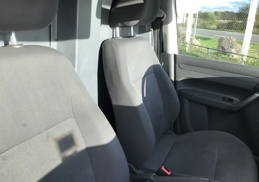 Vue intérieure sur les sièges avant en tissu noir du Volkswagen Caddy Maxi Van frigo, avec portière côté droit visible.