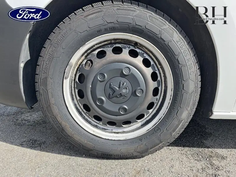 Gros plan sur la roue avant gauche du Peugeot Expert Fourgon blanc Banquise, montrant la jante acier avec logo lion central.