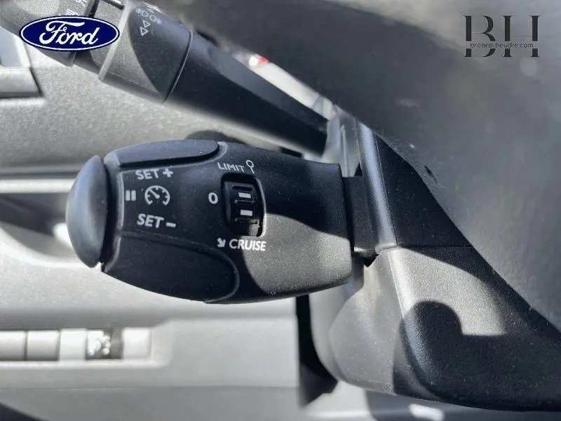 Gros plan sur la commande de régulateur de vitesse noire dans l'habitacle d'un Peugeot Expert Fourgon blanc Banquise.