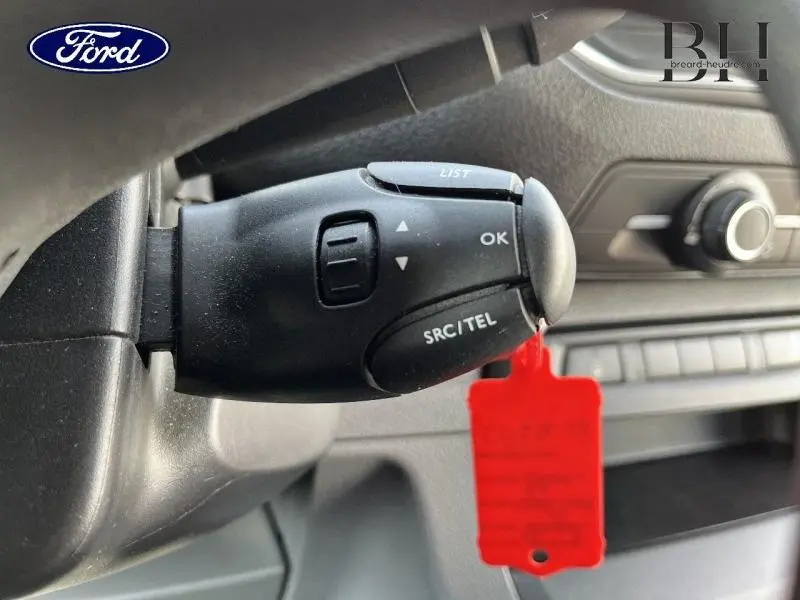 Commande au volant noir en gros plan dans l'habitacle d'un Peugeot Expert Fourgon blanc Banquise, avec tableau de bord en arrière-plan flou.