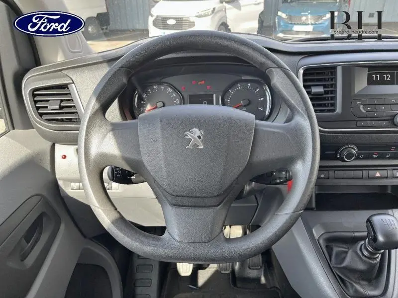 Vue intérieure centrée sur le volant Peugeot d'un Expert Fourgon blanc avec tableau de bord et levier de vitesses manuel.
