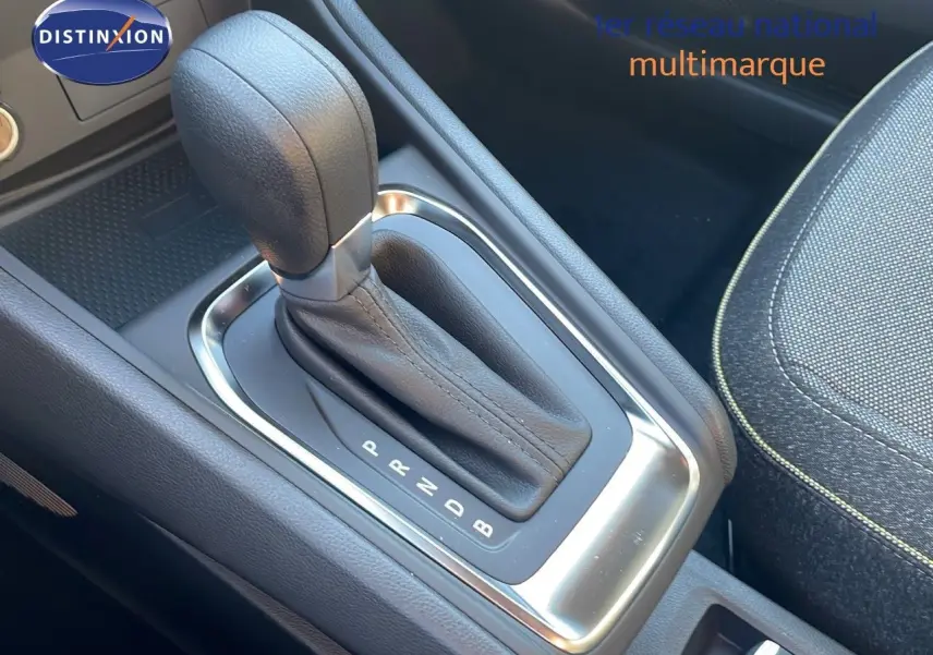 Le levier de vitesse automatique en cuir noir du Renault Captur E-Tech hybride, avec console centrale et siège tissu gris.