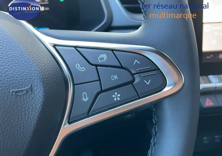 Gros plan sur les commandes multifonctions côté gauche du volant d’un Renault Captur blanc nacré 2025 hybride.