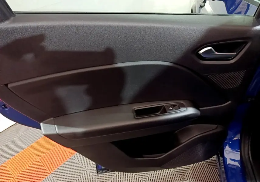Vue intérieure de la porte arrière droite du Renault Captur bleu 2023, avec poignée et commande de fenêtre noire.