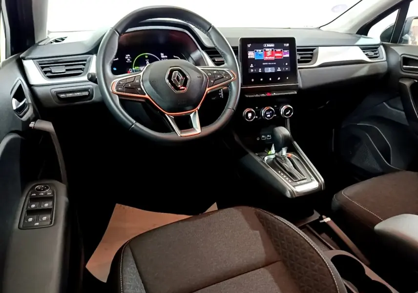 Vue intérieure avant du Renault Captur 2023, tableau de bord noir avec écran tactile central et volant multifonctions.