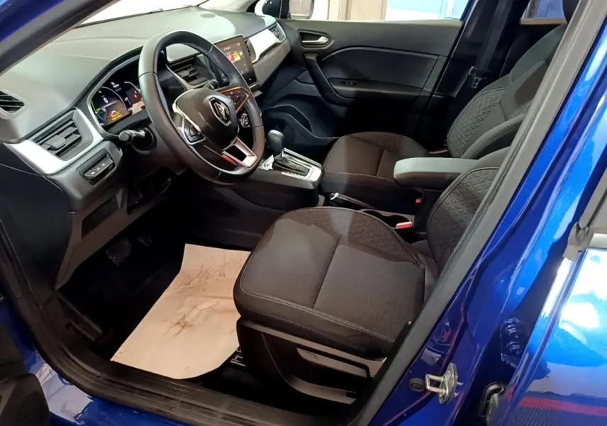 Vue intérieure côté conducteur du Renault Captur bleu 2023, avec volant multifonctions et sièges noirs tissu.