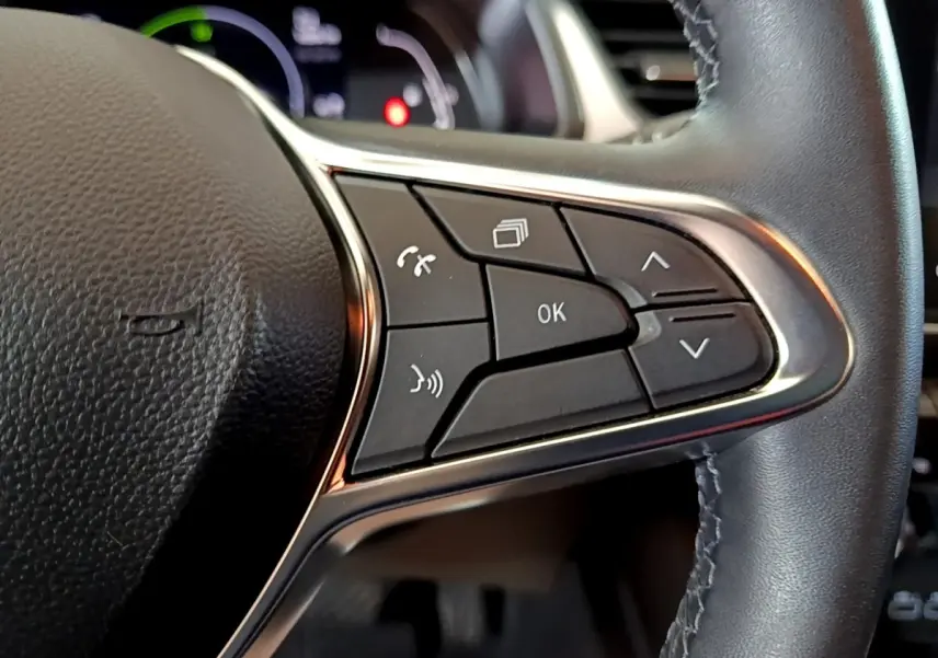 Gros plan sur les commandes multifonctions à droite du volant cuir noir du Renault Captur bleu hybride 2023.