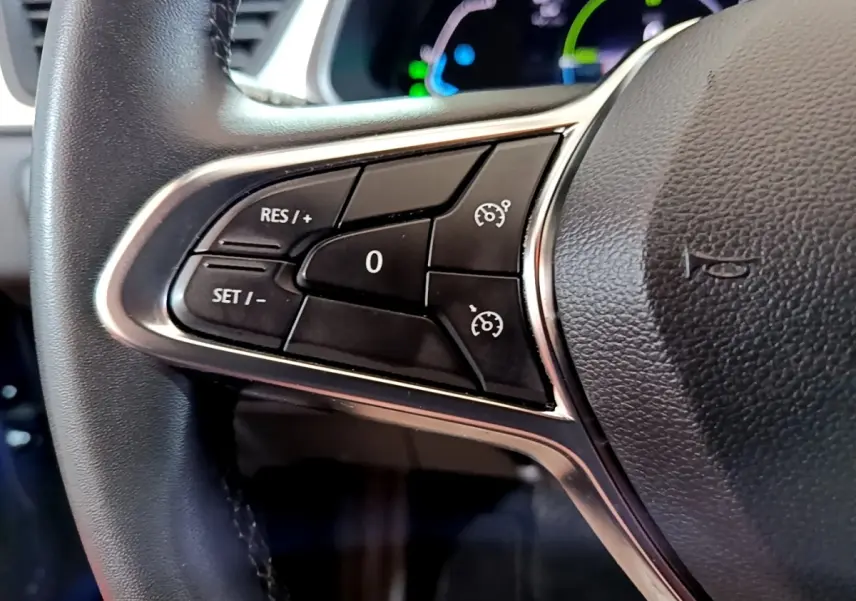 Gros plan sur les commandes de régulateur de vitesse à gauche du volant noir du Renault Captur bleu hybride 2023.