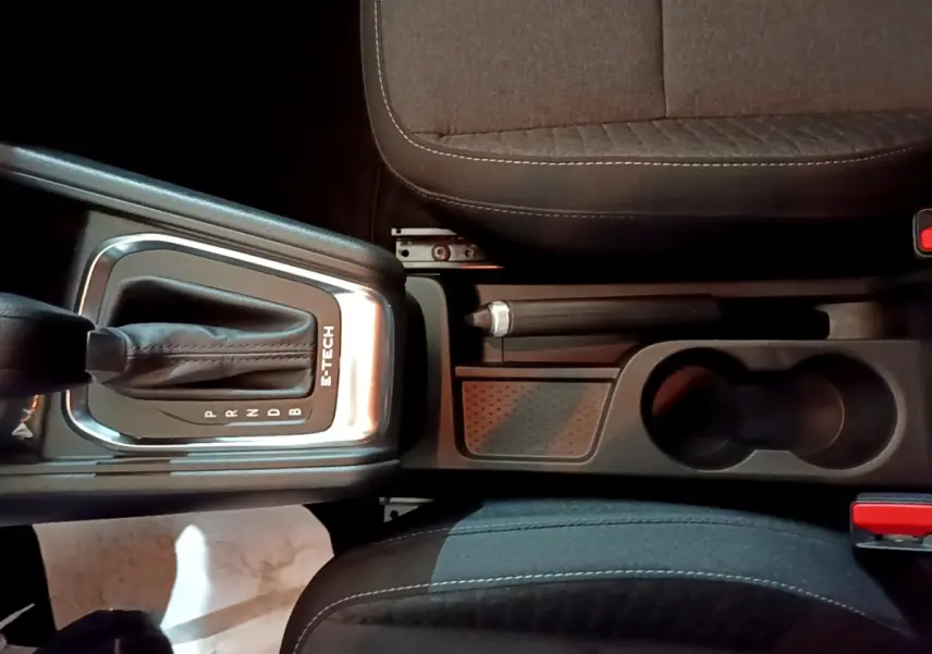 Vue plongeante sur la console centrale noire du Renault Captur E-Tech avec levier de vitesses automatique et frein à main manuel.