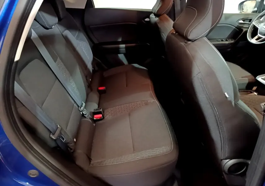 Vue intérieure côté arrière gauche du Renault Captur bleu, montrant la banquette arrière en tissu noir avec ceintures de sécurité.