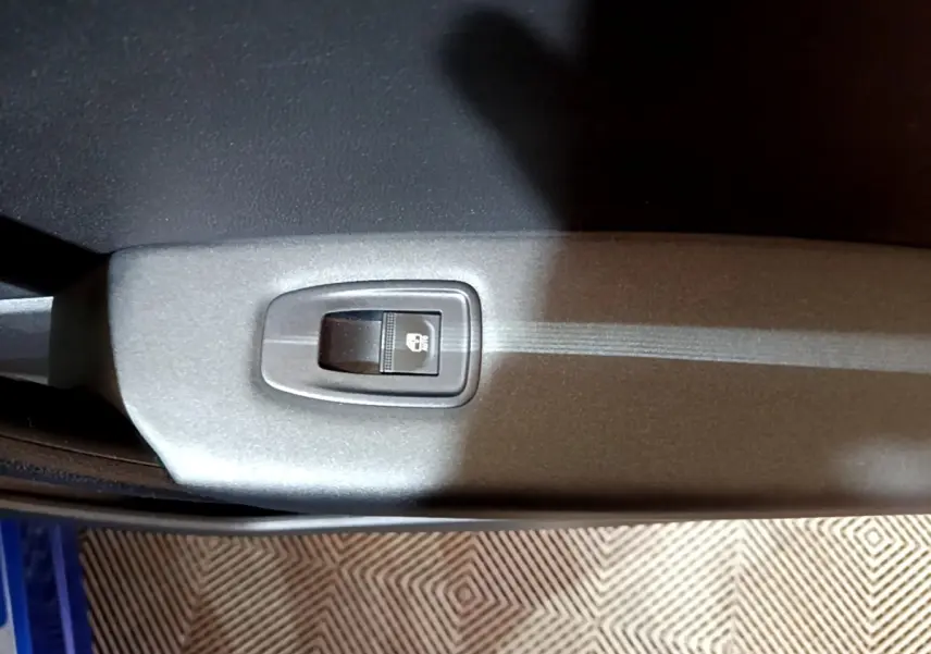 Gros plan sur le bouton de verrouillage des portes dans l'habitacle du Renault Captur bleu, côté intérieur de porte.