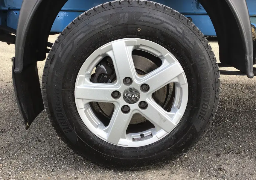 Gros plan sur la roue avant gauche du Volkswagen Crafter bleu, jante alliage cinq branches et pneu Bridgestone.