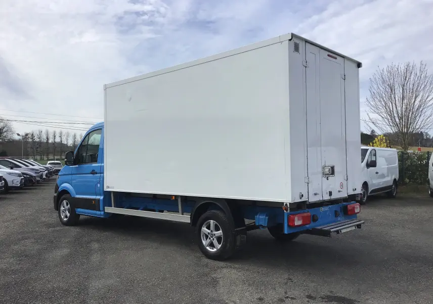 Vue 3/4 arrière droite du Volkswagen Crafter bleu avec caisse blanche, portes arrière fermées et jantes alliage 16 pouces.