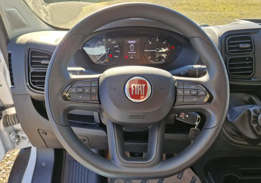 Vue rapprochée du volant noir du Fiat Ducato Chassis Benne 2023 avec tableau de bord et commandes visibles.