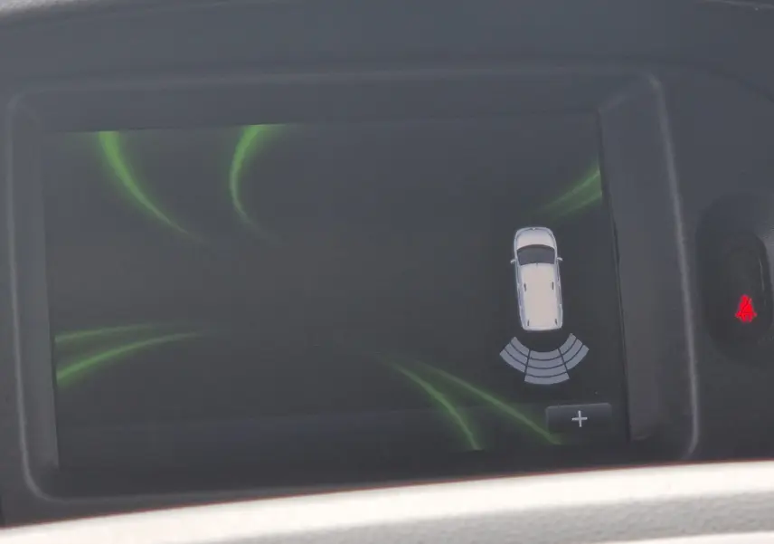 Écran de bord du Renault Kangoo blanc 2020 montrant l'alerte de proximité arrière avec capteurs actifs.