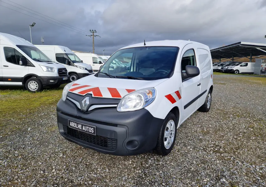 Vue 3/4 avant d’un Renault Kangoo blanc 2020 avec bandes rouges réfléchissantes sur capot et ailes, stationné sur gravier.