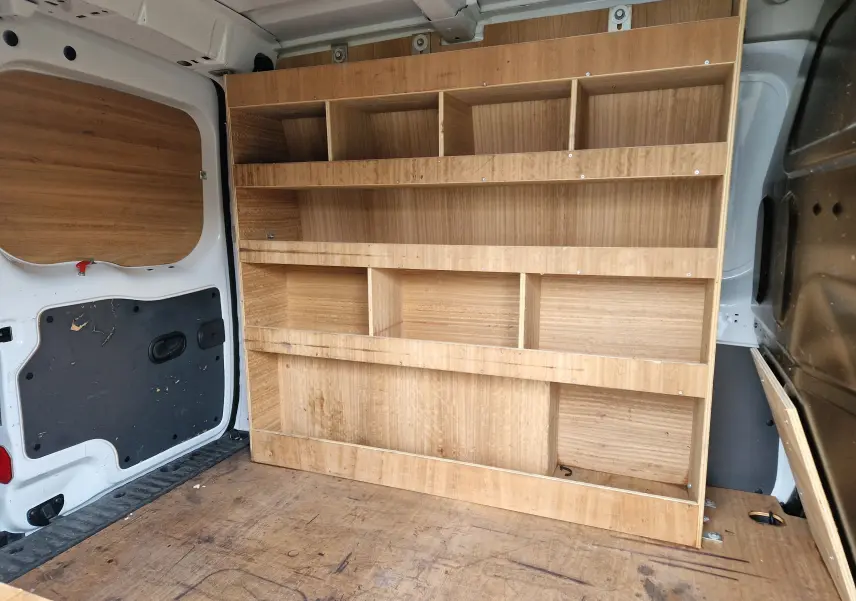 Vue intérieure arrière du Renault Kangoo blanc 2020, montrant les étagères en bois intégrées au compartiment de chargement.