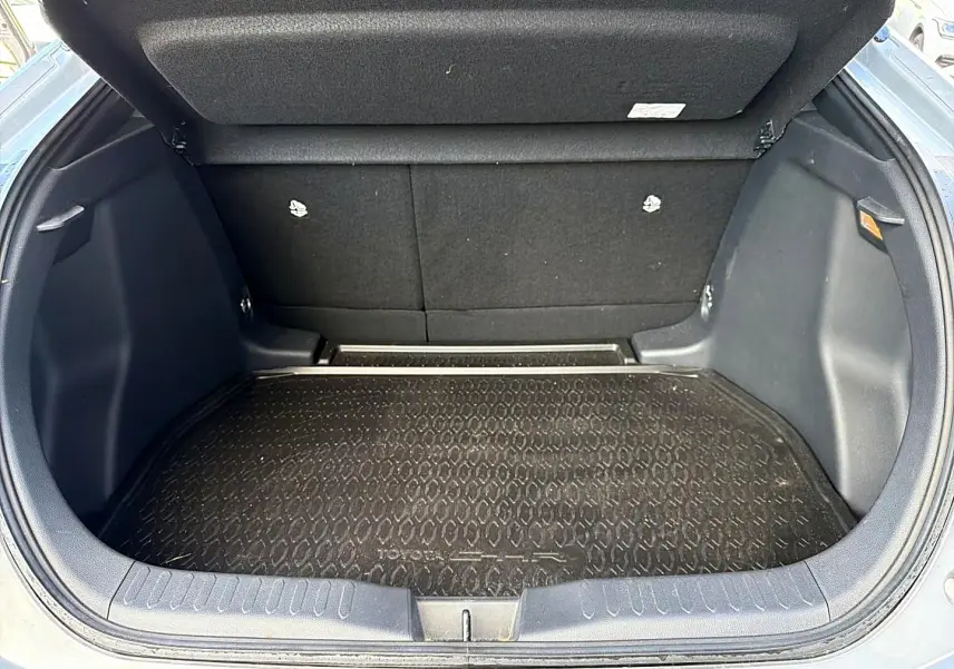 Coffre ouvert d’un Toyota C-HR gris, vue arrière montrant la surface de chargement avec tapis de protection noir.