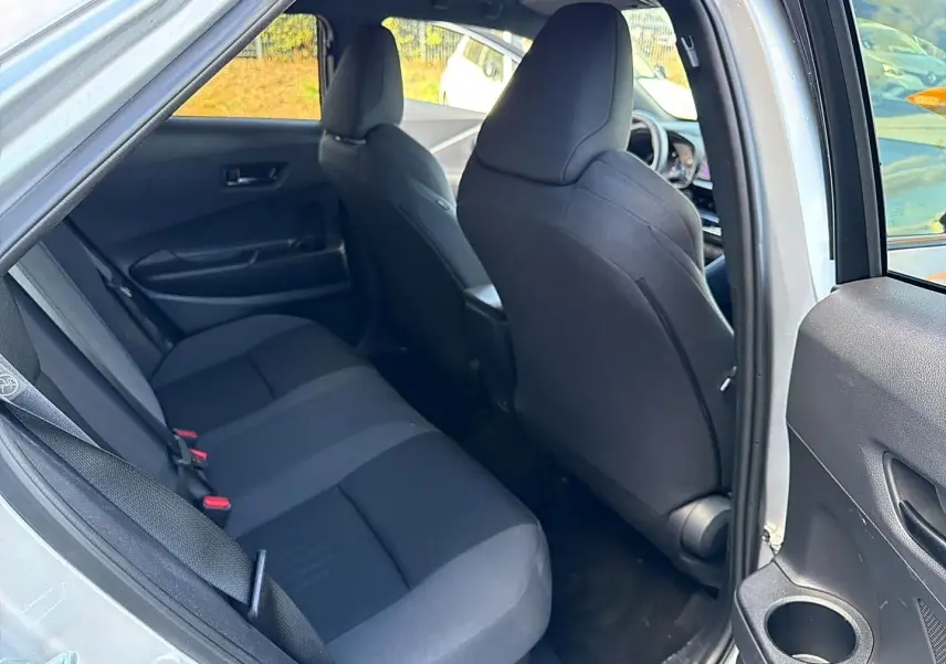 Vue intérieure côté gauche sur la banquette arrière et sièges avant noirs du Toyota C-HR gris 2025 hybride.
