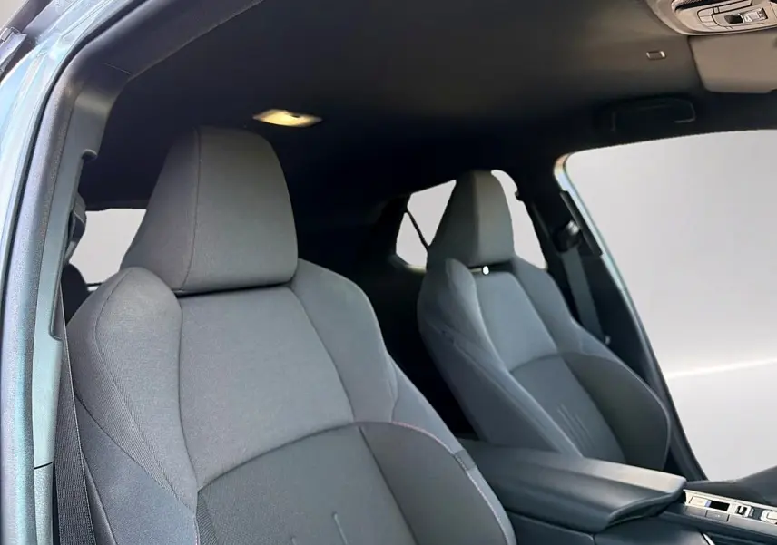 Vue intérieure sur les sièges avant gris foncé du Toyota C-HR 1.8 hybride 2025 avec accoudoir central.