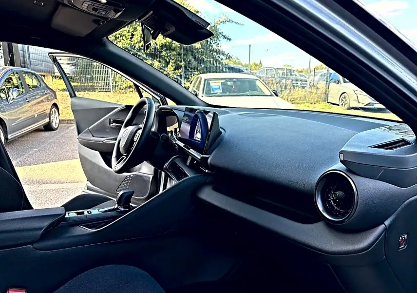 Intérieur du Toyota C-HR 1.8 hybride 2025 vu côté conducteur, tableau de bord noir avec écran tactile central.