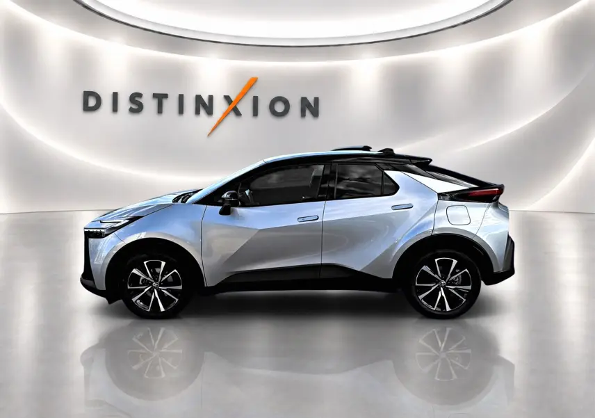 Profil côté gauche d'un Toyota C-HR gris 2025 avec jantes alliage et toit noir dans un showroom lumineux.