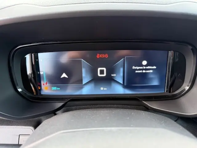 Tableau de bord numérique du Citroën Berlingo blanc 2026, affichant 0 km/h et un message d'alerte.