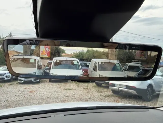 Vue arrière dans le rétroviseur intérieur d'un Citroën Berlingo blanc 2026, version van diesel, sur un parking.