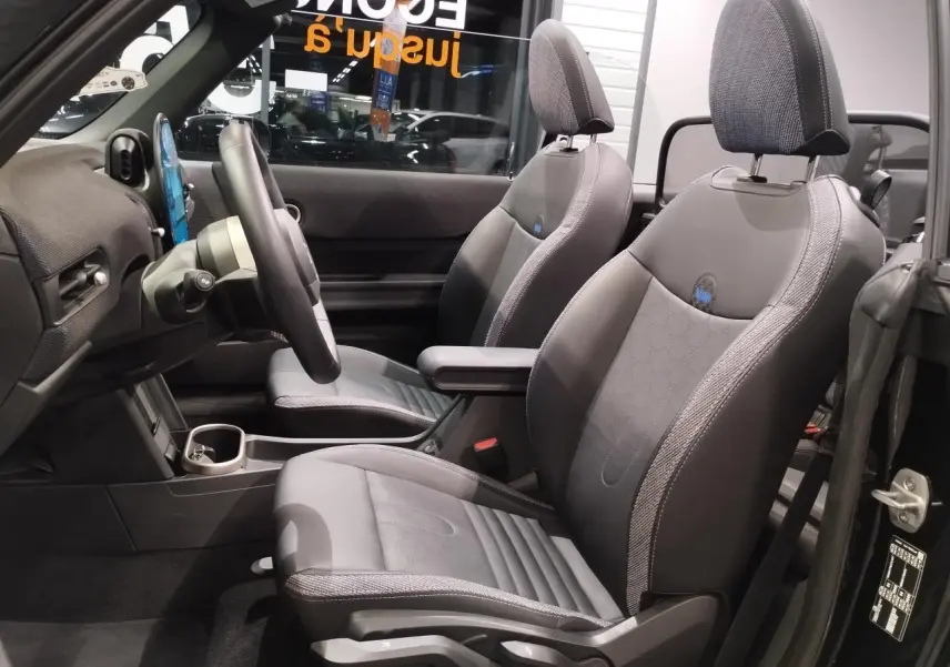 Vue intérieure côté conducteur du cabriolet MINI noir 2025 avec sièges sport en similicuir perforé noir et accoudoir central.