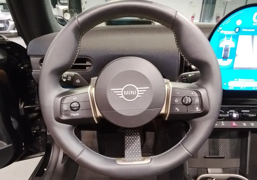 Volant cuir noir multifonction de la MINI Cabriolet 2025 avec tableau de bord et écran tactile visible à droite.