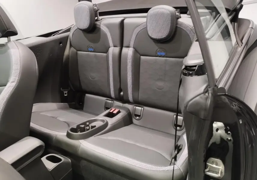Vue intérieure arrière du cabriolet MINI noir, montrant les sièges arrière en similicuir perforé avec logo MINI brodé.