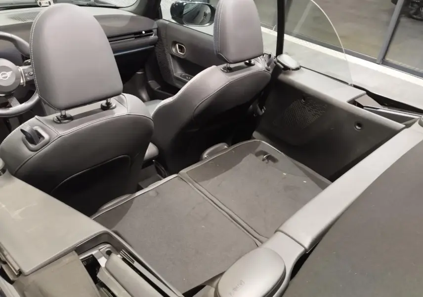 Vue intérieure arrière du cabriolet MINI noir 2025, sièges avant en similicuir perforé noir avec motifs bleus.