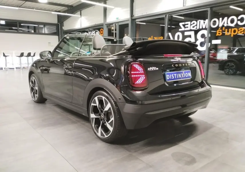Vue 3/4 arrière droite d'une MINI Cabriolet noire avec capote souple repliée et feux arrière à LED Union Jack.