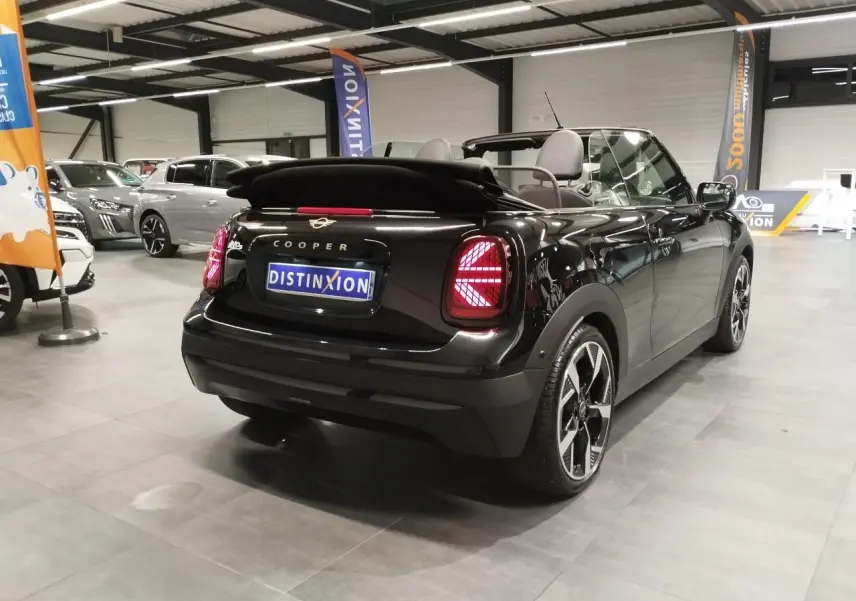Vue 3/4 arrière droite d'une MINI Cabriolet noire avec capote souple repliée et feux arrière à LED Union Jack.