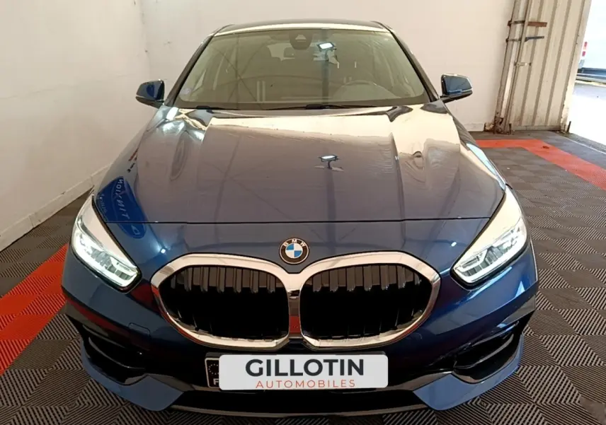 Vue avant rapprochée d’une BMW Série 1 118i Edition Sport bleu avec calandre double haricot et phares LED allumés.
