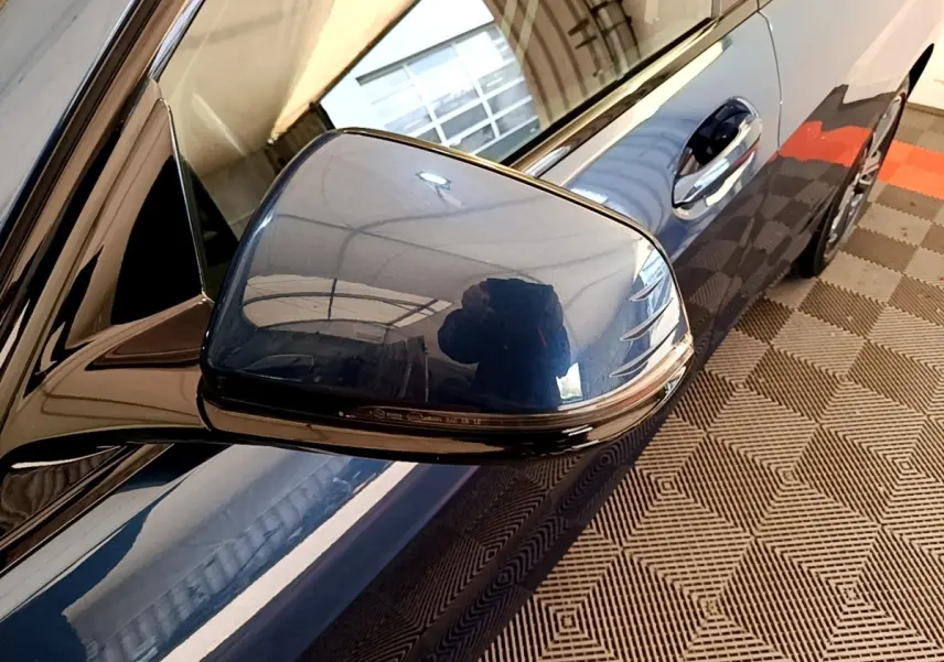 Gros plan sur le rétroviseur droit bleu métallisé de la BMW Série 1 118i Edition Sport 2023, avec poignée de porte visible.