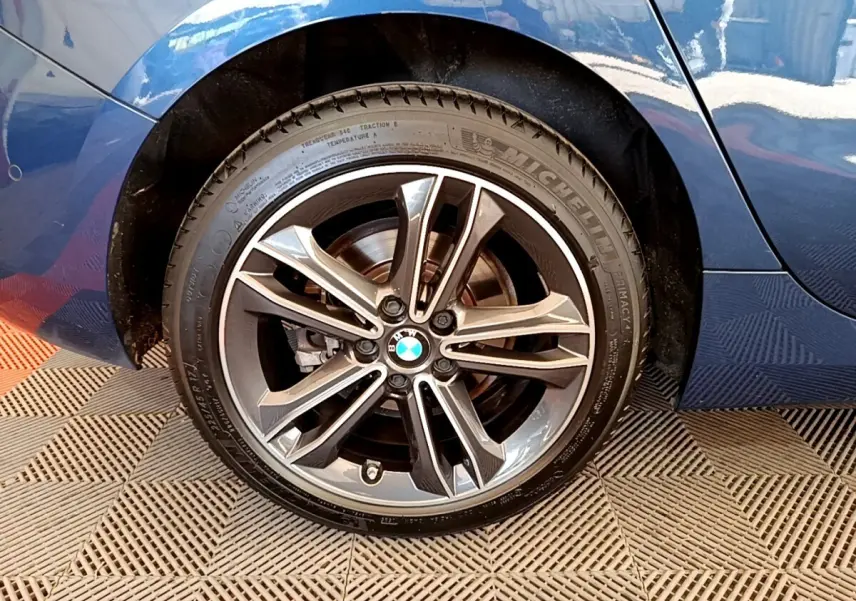 Gros plan sur la roue arrière droite d'une BMW Série 1 bleu avec jante alliage et pneu Michelin.