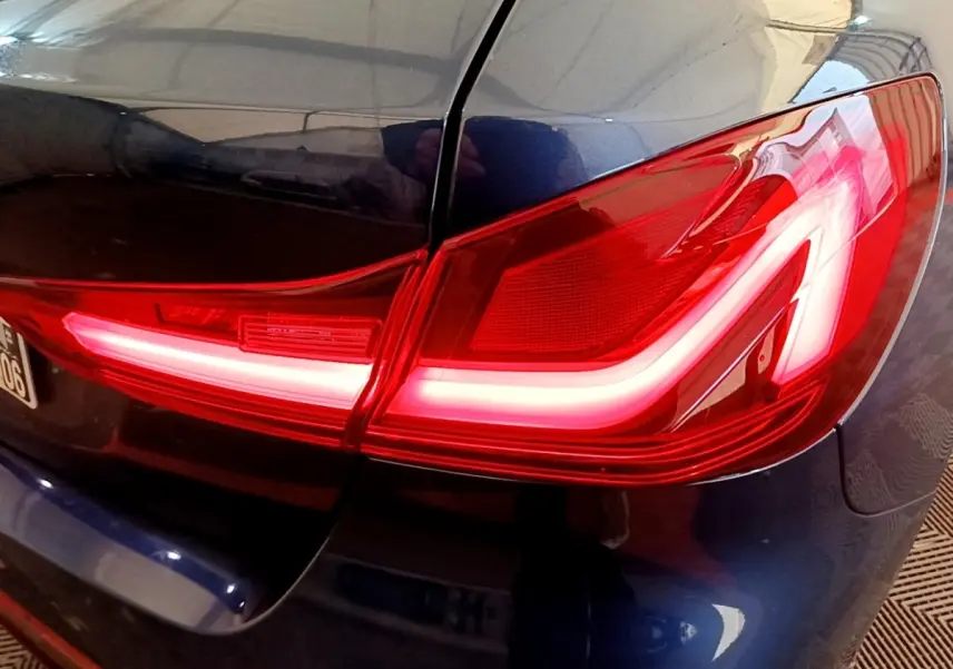 Gros plan sur le feu arrière droit rouge allumé d’une BMW Série 1 118i Edition Sport bleu 2023.