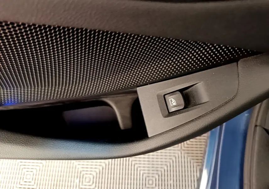 Détail de la commande de lève-vitre sur la porte côté conducteur d’une BMW Série 1 bleu 118i Edition Sport 2023.