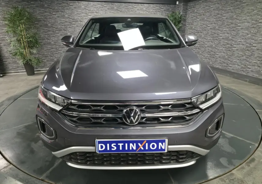 Vue avant d'un Volkswagen T-Roc gris métallisé 2024 avec calandre chromée et logo VW bien visible