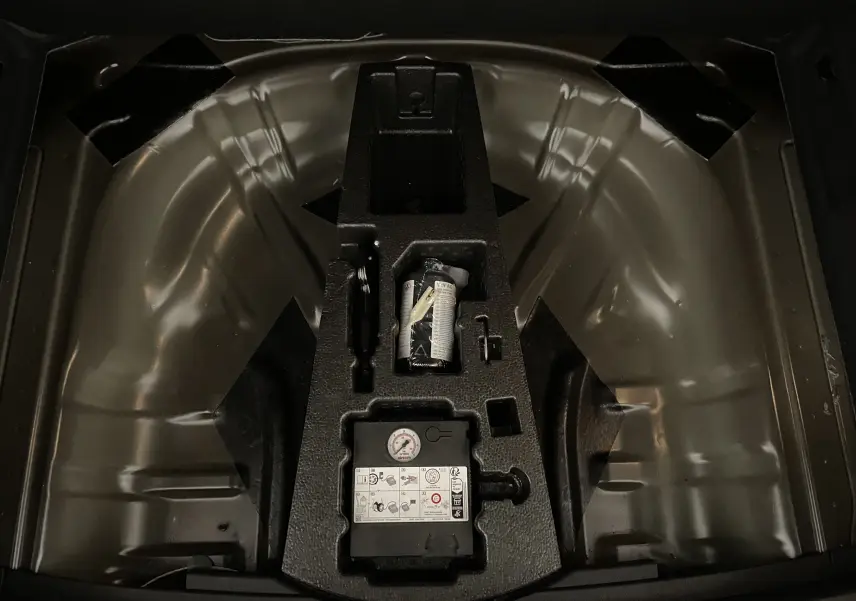 Gros plan sur le compartiment de roue de secours du Skoda Karoq 2023, montrant le kit de réparation pneumatique intégré.