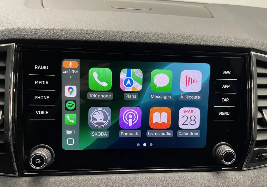 Écran tactile central du Skoda Karoq 2023 affichant l'interface Apple CarPlay avec commandes autour.