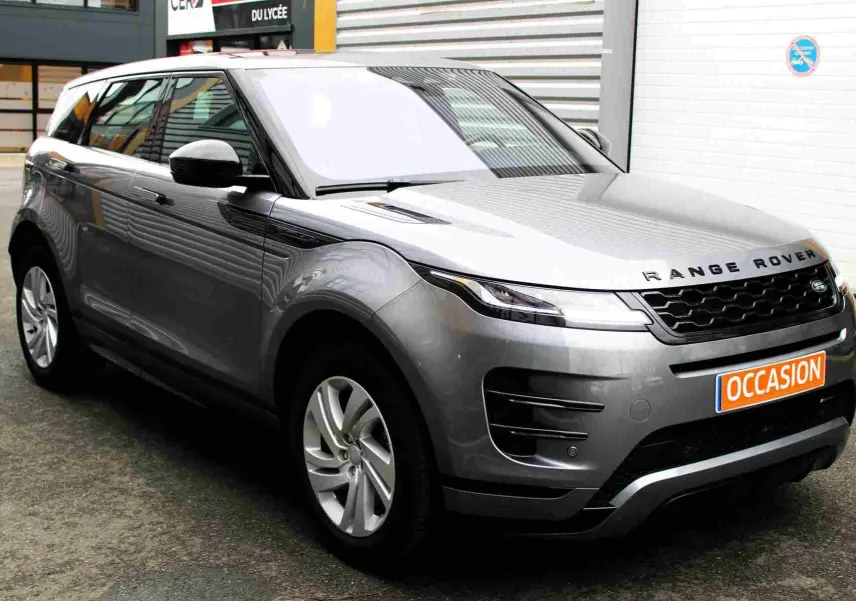 Range Rover Evoque gris métal en 3/4 avant droit, avec calandre noire et plaque "OCCASION" orange visible.