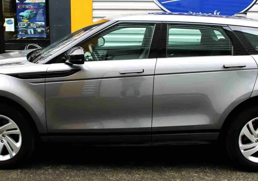 Vue de profil côté gauche du Range Rover Evoque 2023 gris métal, soulignant ses lignes épurées et ses jantes alliage.