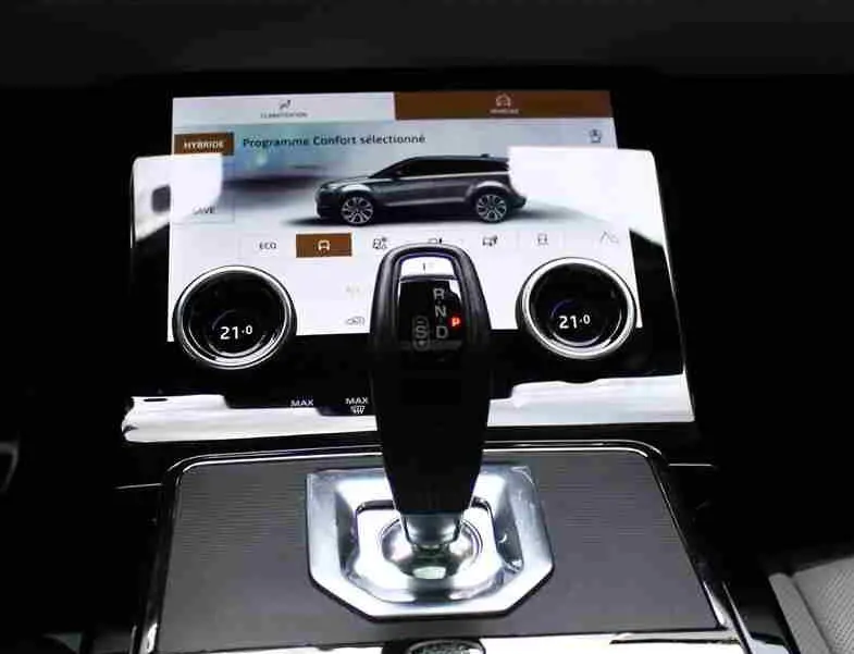Vue rapprochée de la console centrale du Range Rover Evoque gris métal 2023 avec écran tactile et levier de vitesse moderne.